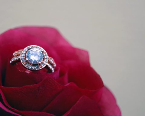 closeup photography of clear jeweled gold colored cluster ring on red rose